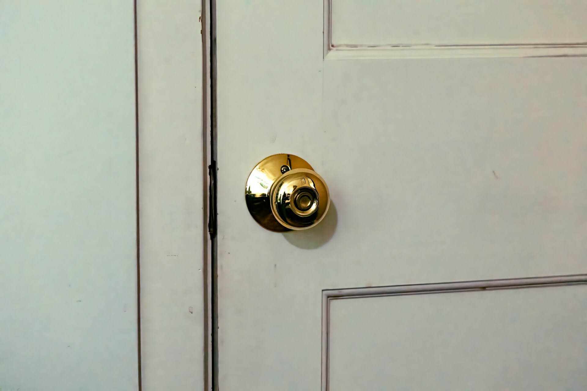 A close-up of a gold doorknob on a white door